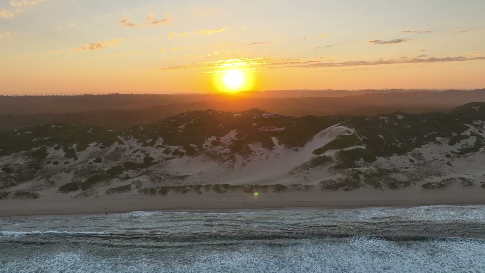Golden sunset light drifting over the reserve's dunes, bush and surf